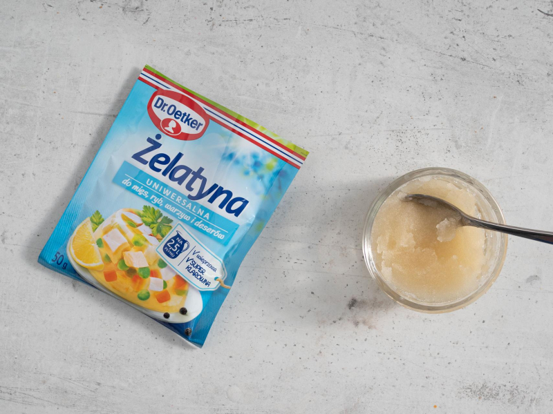 Opakowanie żelatyny na blacie kuchennym, a obok żelatyna namoczona w miseczce.