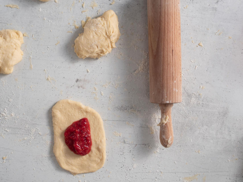 Rozwałkowany placek ciasta z nadzieniem malinowym.