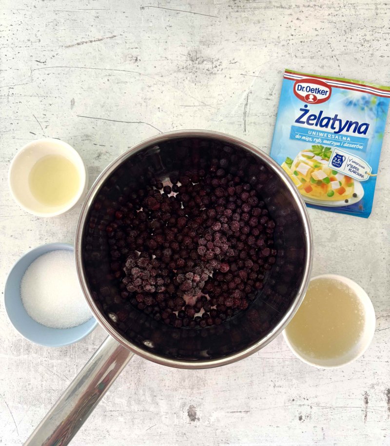 mrożone jagody w garnuszku, obok żelatyna, cukier i sok z cytryny