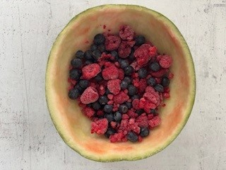 w połówce arbuza wrzucone owoce (jagody, borówki, maliny)