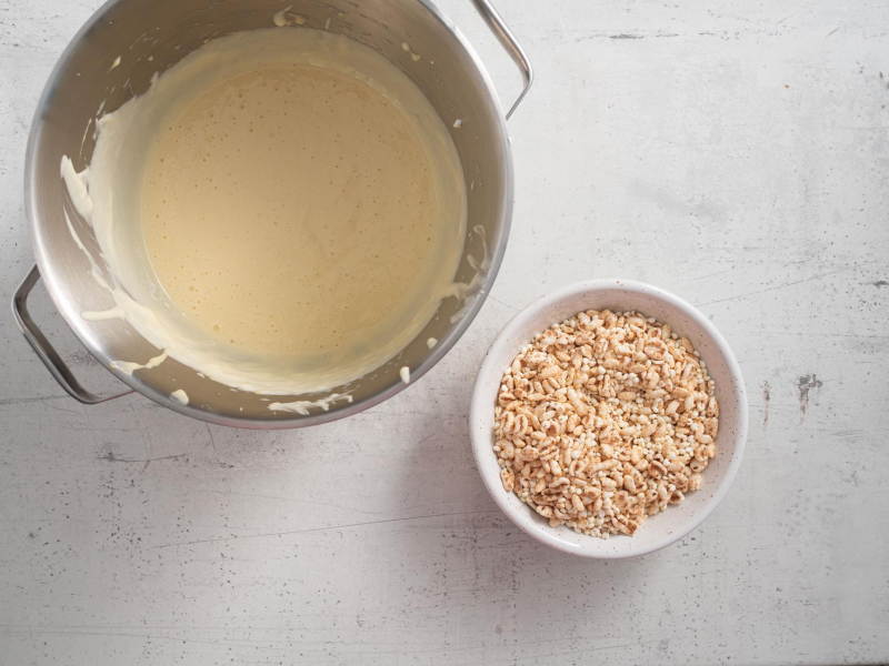 W dużej misie wymieszana biała masa proteinowa na kinder country. Obok preparowany owies w miseczce.