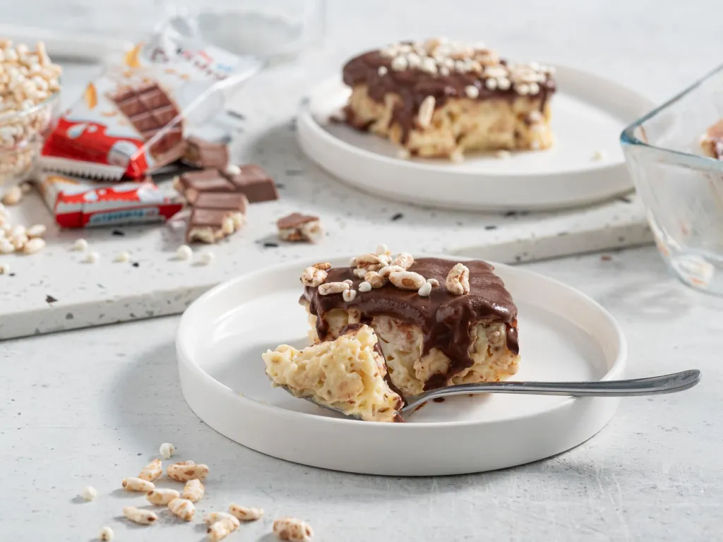 Kawałek proteinowego deseru kinder country z czekoladą, na białym talerzyku - Wszystkiego Słodkiego