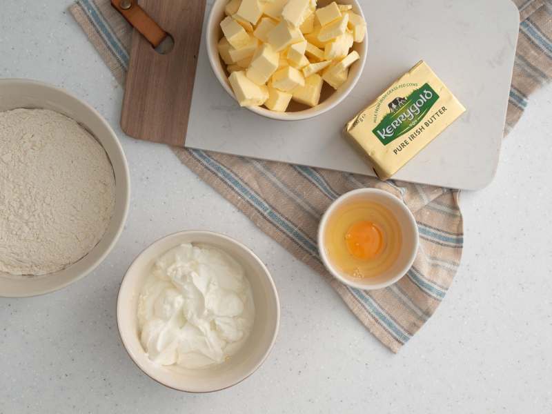 W miseczce twaróg, jajko. Obok masło pokrojone w kostkę.
