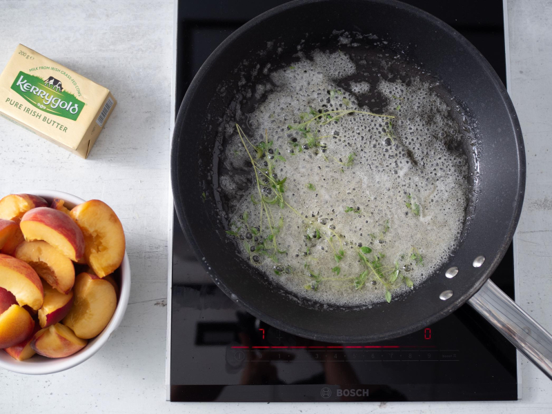 patelnia z rozpuszczonym masłem i świeżym tymiankiem