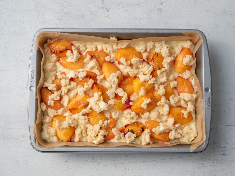 ciasto z budyniem i brzoskwiniami w dużej blaszce przed pieczeniem