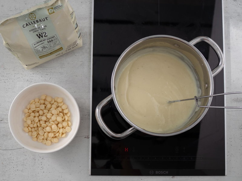 w garnku ugotowany budyń obok biała czekolada w kaletkach Callebaut