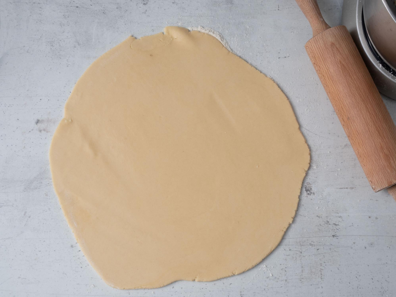 rozwałkowane ciasto na tartę na blacie obok derwniany wałek