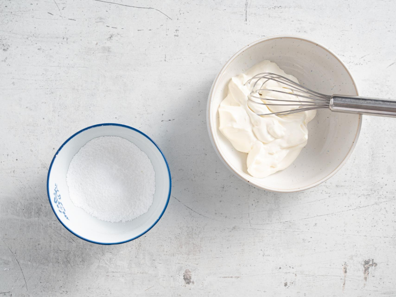 W jednej misce cukier puder, a w drugiej śmietana.