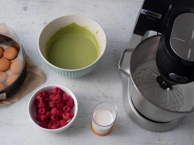 w miseczce maliny, masa jogurtowa z matchą i ubita śmietanka w robocie bosch