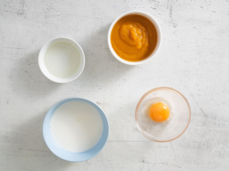 W miseczkach mleko, olej, żółtko oraz puree z dyni.