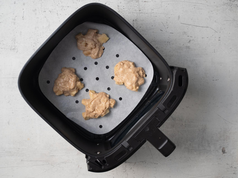 Ciasto na racuchy z jabłkami wyłożone na papierze do pieczenia.