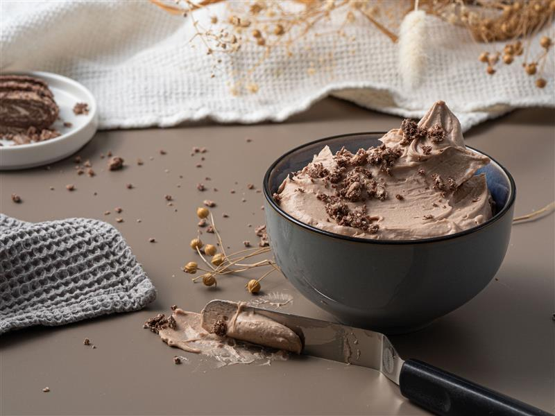 krem chałwowy w miseczce, obok szpatułka do tortów z odrobiną kremu