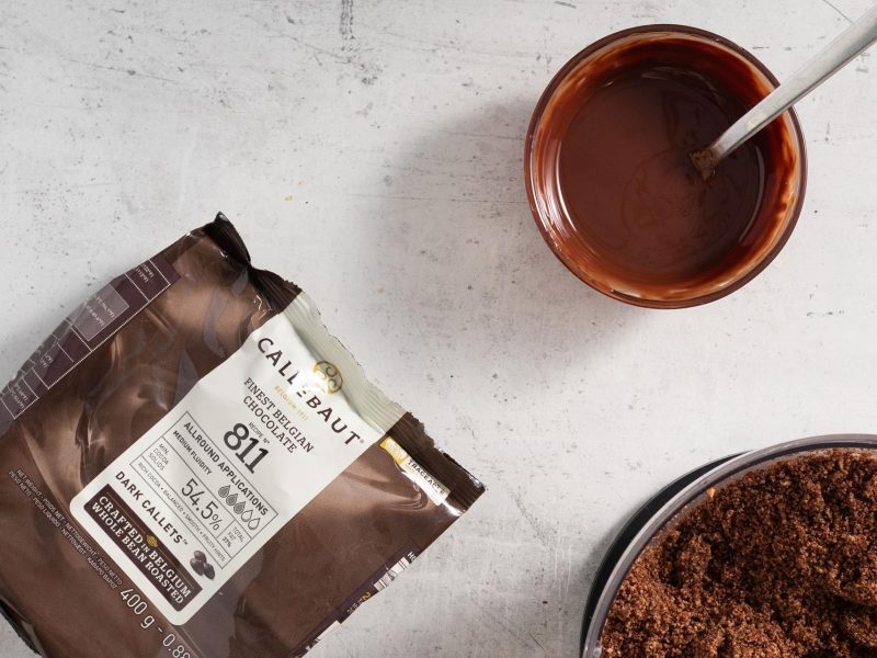 Na blacie kuchennym opakowanie czekolady. W miseczce rozpuszczona czekolada z olejem.