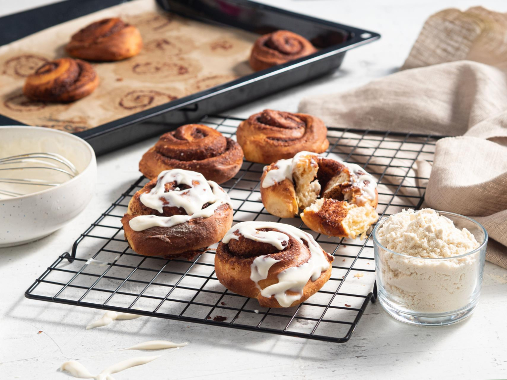 Proteinowe cynamonki polane serkiem proteinowym studzące się na kratce do pieczenia - przepis Wszystkiego Słodkiego