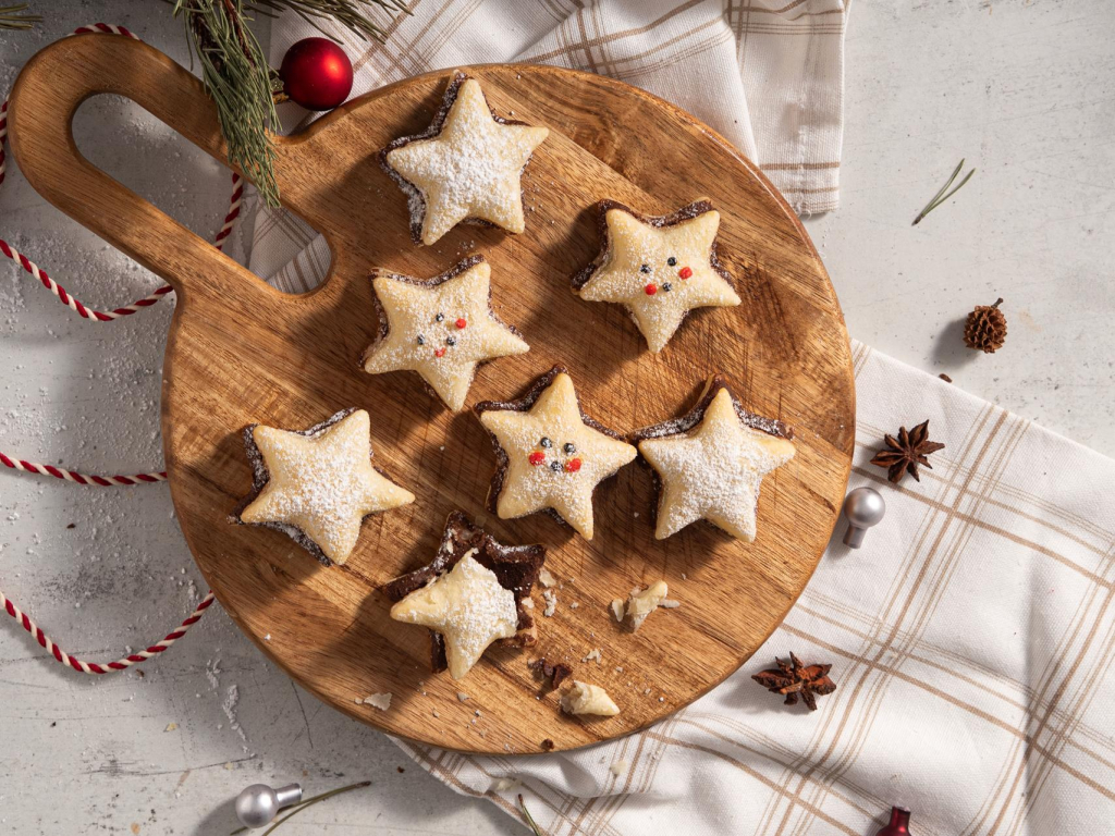 Francuskie ciasteczka z czekoladą oprószone cukrem pudrem na drewnianej paterze w otoczeniu ozdób świątecznych - przepis Wszystkiego Słodkiego