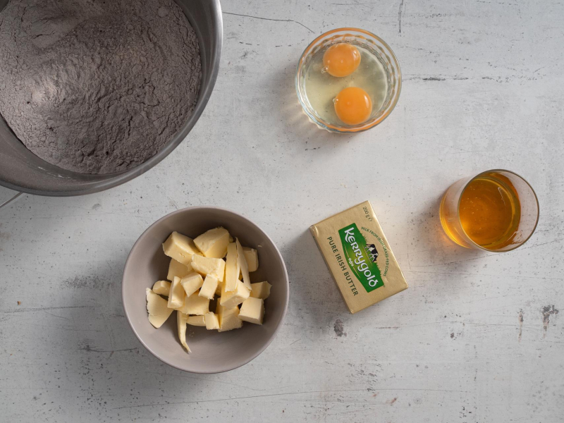 Na blacie kuchennym składniki do pierniczków (masło, miód oraz jajka)