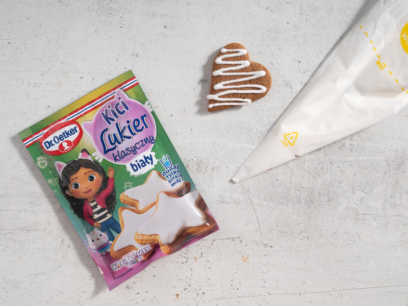 Udekorowane pierniczek lukrem. Obok opakowanie z gotowym lukrem.