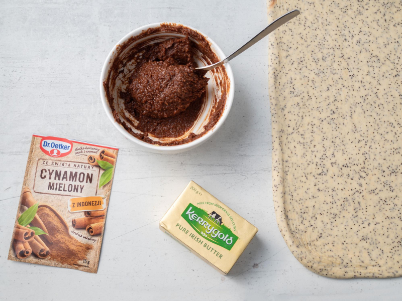 opakowanie cynamonu Dr. Oetker na blacie obok masło Kerrygold o rozwałkowane ciasto z makiem