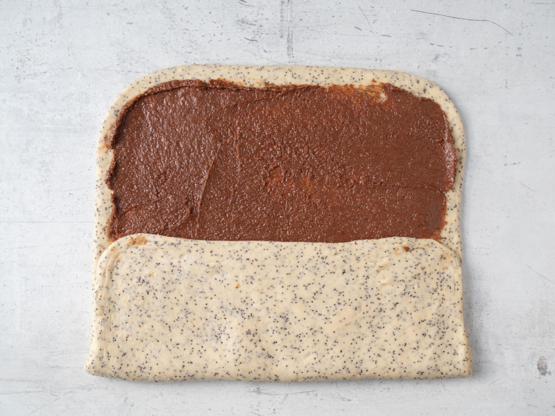 rozwałkowane i złożone do połowy ciasto drożdżowe z cynamonowym nadzieniem