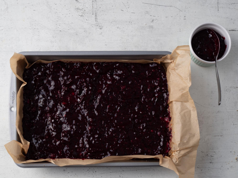 warstwa porzeczkowa na cieście w foremce obok frużelina z owoców