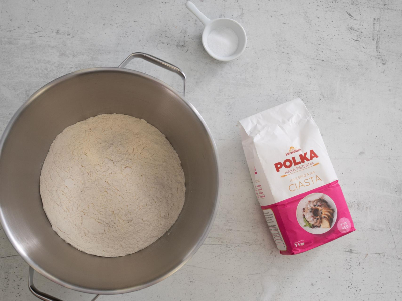 Na blacie kuchennym opakowanie mąki. Obok sól oraz mąka w misie.