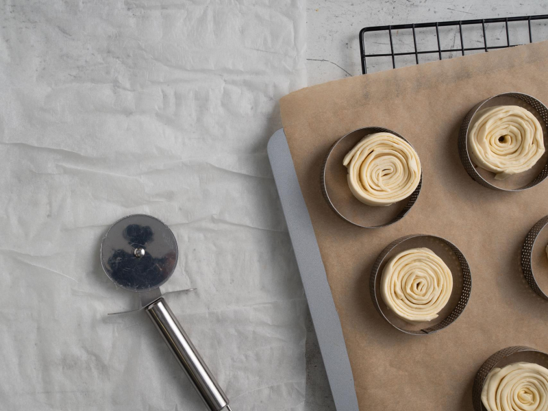 Na blacie kuchennym radełko. Obok zwinięte rollsy z gotowego ciasta francuskiego.