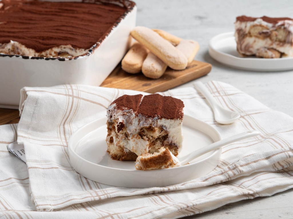 Proteinowe tiramisu z serka wiejskiego na białym talerzyku - przepis Wszystkiego Słodkiego