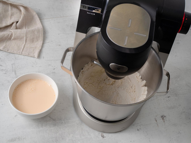 w robocie suche składniki na pączki dubajskie obok miseczka z mlekiem i jajkami