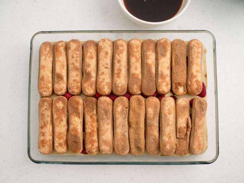 warstwa nasączonych biszkoptów w dużej szklanej formie do tiramisu