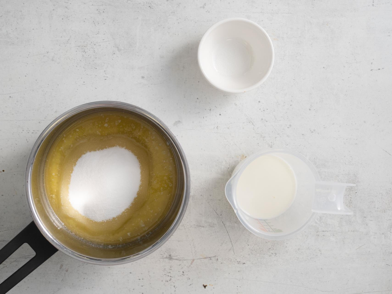 W garnku masło z cukrem. Obok mleko oraz sól.