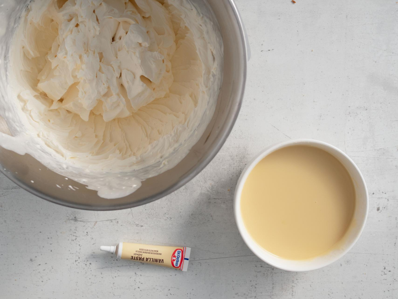 W misie ubita śmietanka z mascarpone. Obok roztopiona biała czekolada oraz ekstrakt waniliowy.