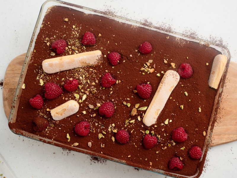 tiramisu pistacjowe duża forma udekorowane malinami i podłużnymi biszkoptami