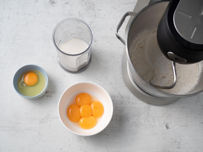 obok robota w miseczkach żółtka, jajko i mleko do babki drożdżowej