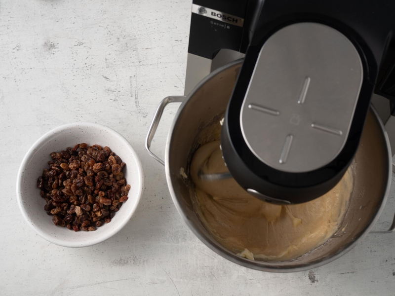 rodzynki w miseczce obok misy z ciastem drożdżowym