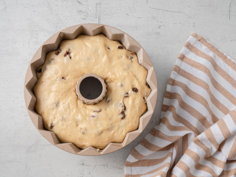 wyrośnięte ciasto drożdżowe z rodzynkami w formie do babki