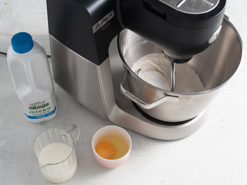 W misie miksera mieszanie suchych składników. Obok w miseczce jajko, i mleko.