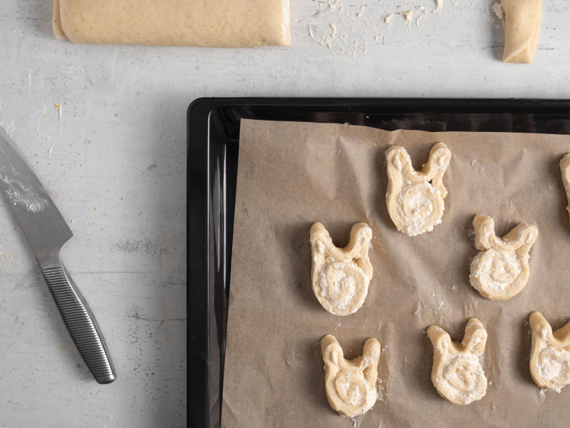 Układanie drożdżowych króliczków na blasze do pieczenia wyłożonej papierem do pieczenia.