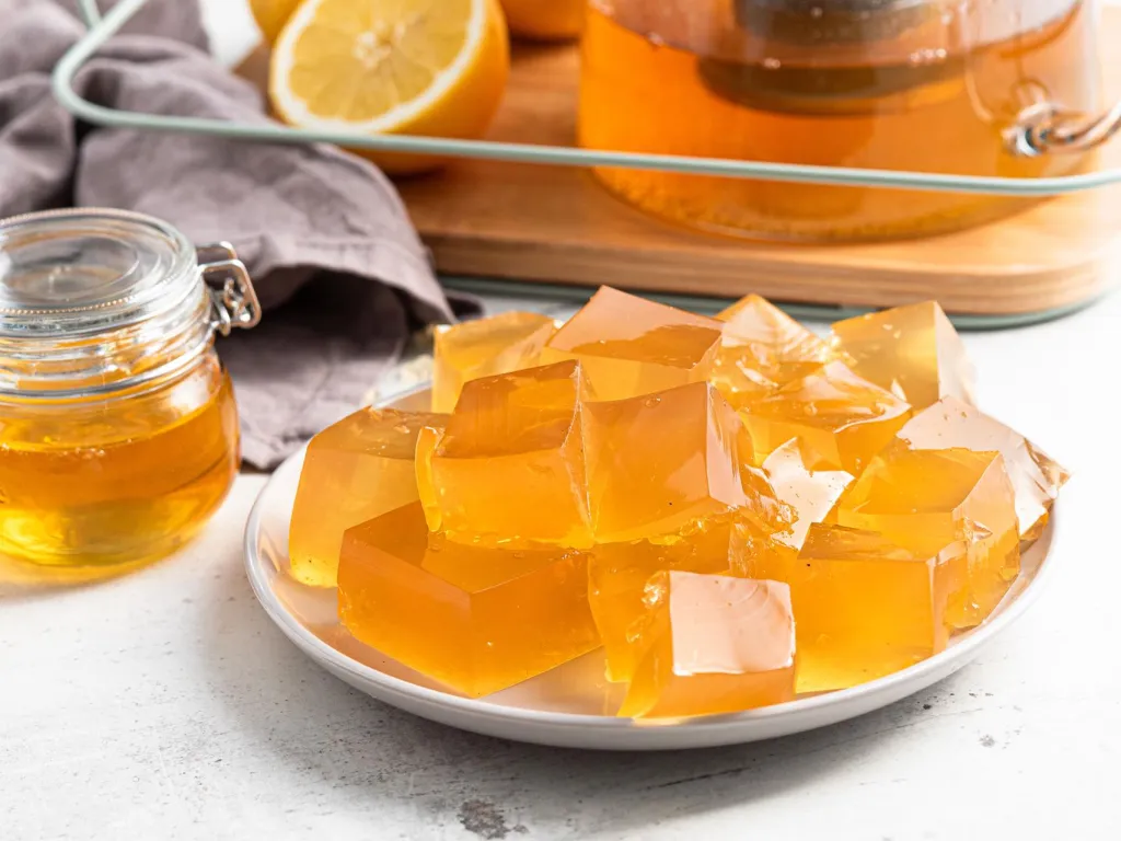 Kolagenowe żelki z zieloną herbatą pokrojone w kostkę na talerzyku - przepis Wszystkiego Słodkiego