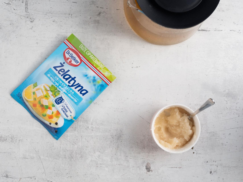 Na blacie kuchennym opakowanie żelatyny, a obok napęczniała żelatyna w miseczce.