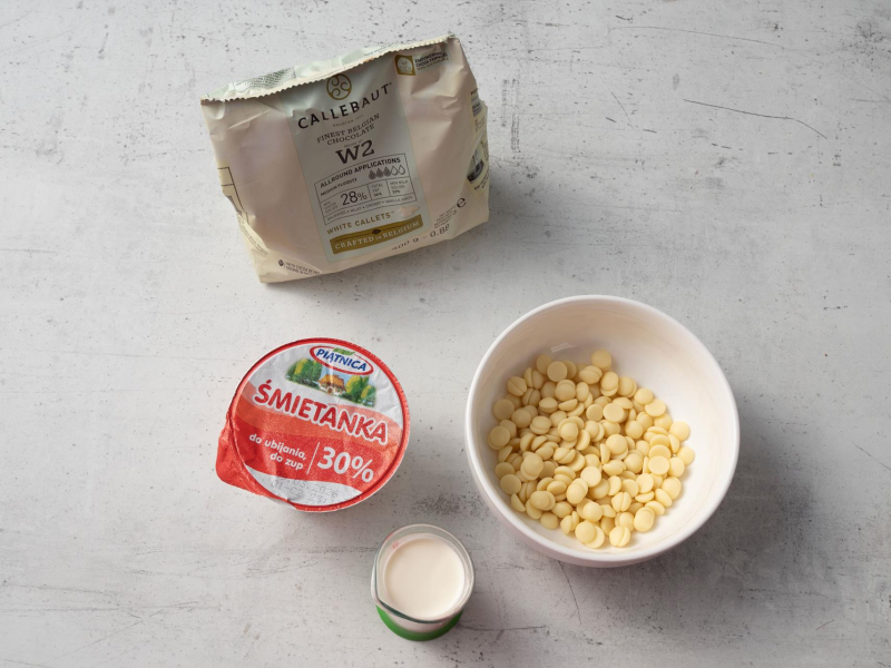 w miseczce kaletki białej czekolady callebaut obok śmietanka