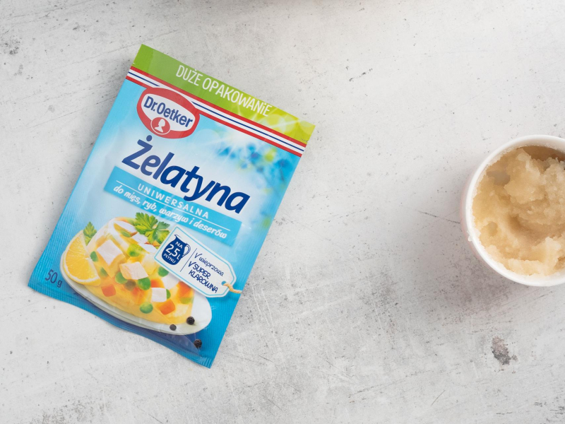 Na blacie kuchennym opakowanie żelatyny. Obok namoczona żelatyna w miseczce..