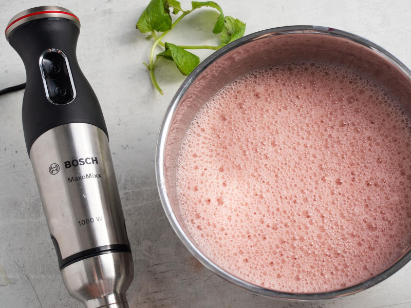 Zmiksowane truskawki w misce w garnku. Obok blender ręczny.
