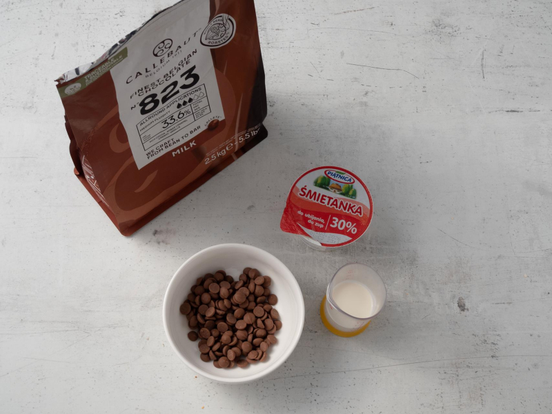 w miseczce kaletki czekolady mlecznej Callebaut obok śmietanka