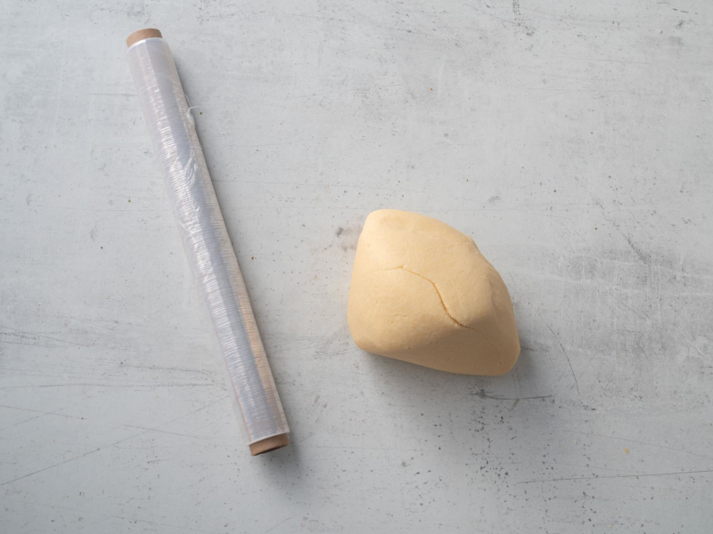 zagniecione w kulkę ciasto kruche obok folia spożywcza