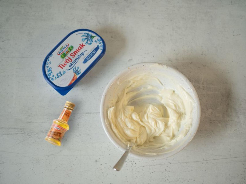 w miseczce wymieszany krem z serka do ciasta marchewkowego obok ekstrakt pomarańczowy dr. oetkera