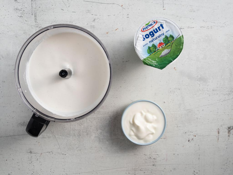 Zmiksowany serek wiejski. Obok opakowanie jogurtu i jogurt w miseczce.