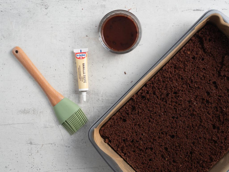 Przekrojone ciasto czekoladowe. Obok nasączenie i pasta z wanilii.