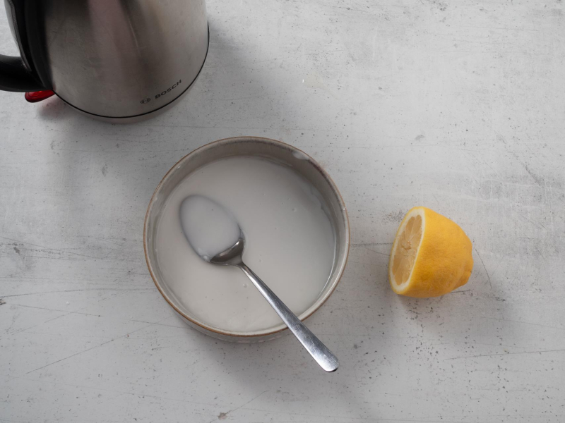 w miseczce wymieszany lukier obok połowa cytryny