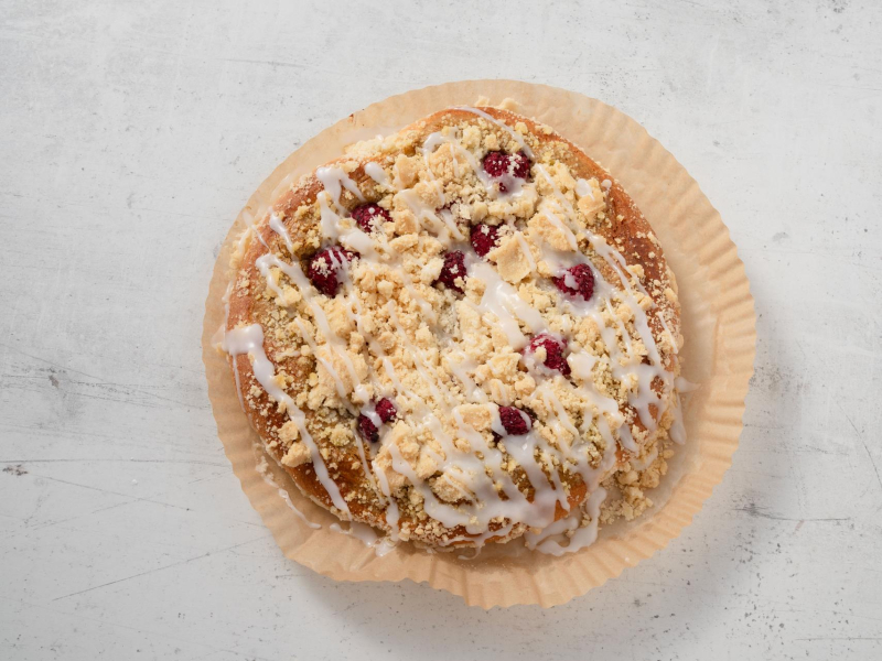 upieczona drożdżówka z budyniem pistacjowym, malinami, kruszonką i lukrem.