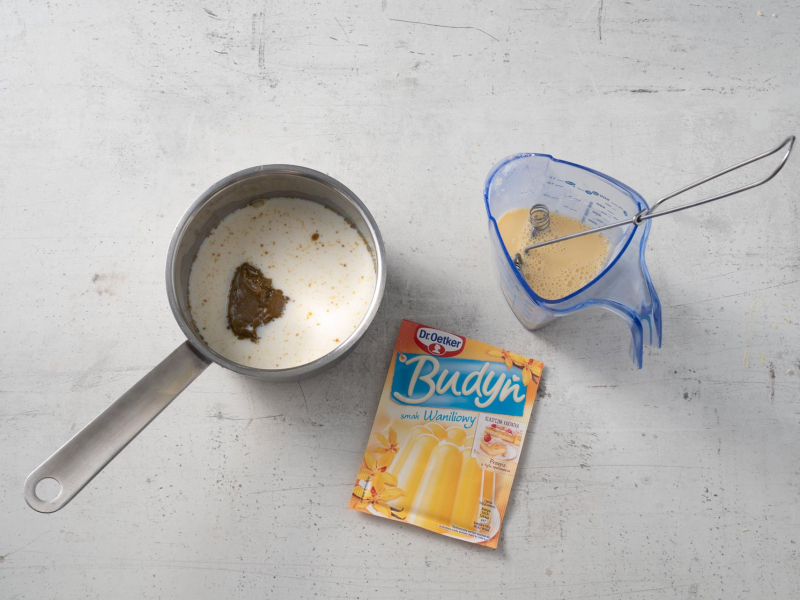 w rondelku mleko obok wymieszany budyń waniliowy Dr. Oetkera